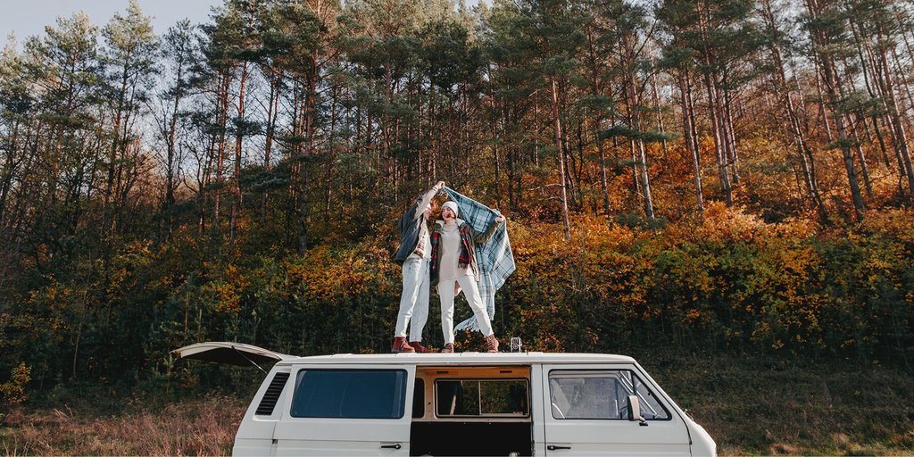 Furgoneta camper estacionada en camping español con toldo y sillas de exterior.