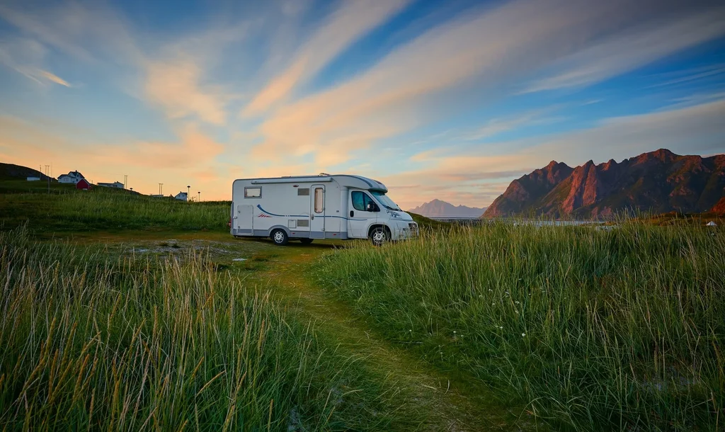 Tent pitched in Peak District valley at dusk, hikers silhouetted against hills.