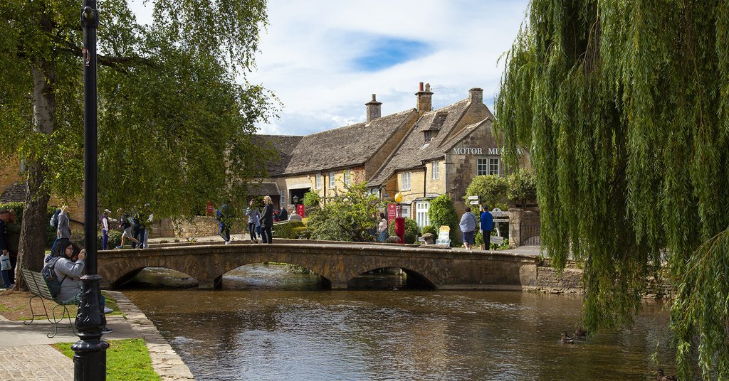 Couple strolling hand-in-hand along the River Windrush in Bourton-on-the-Water.