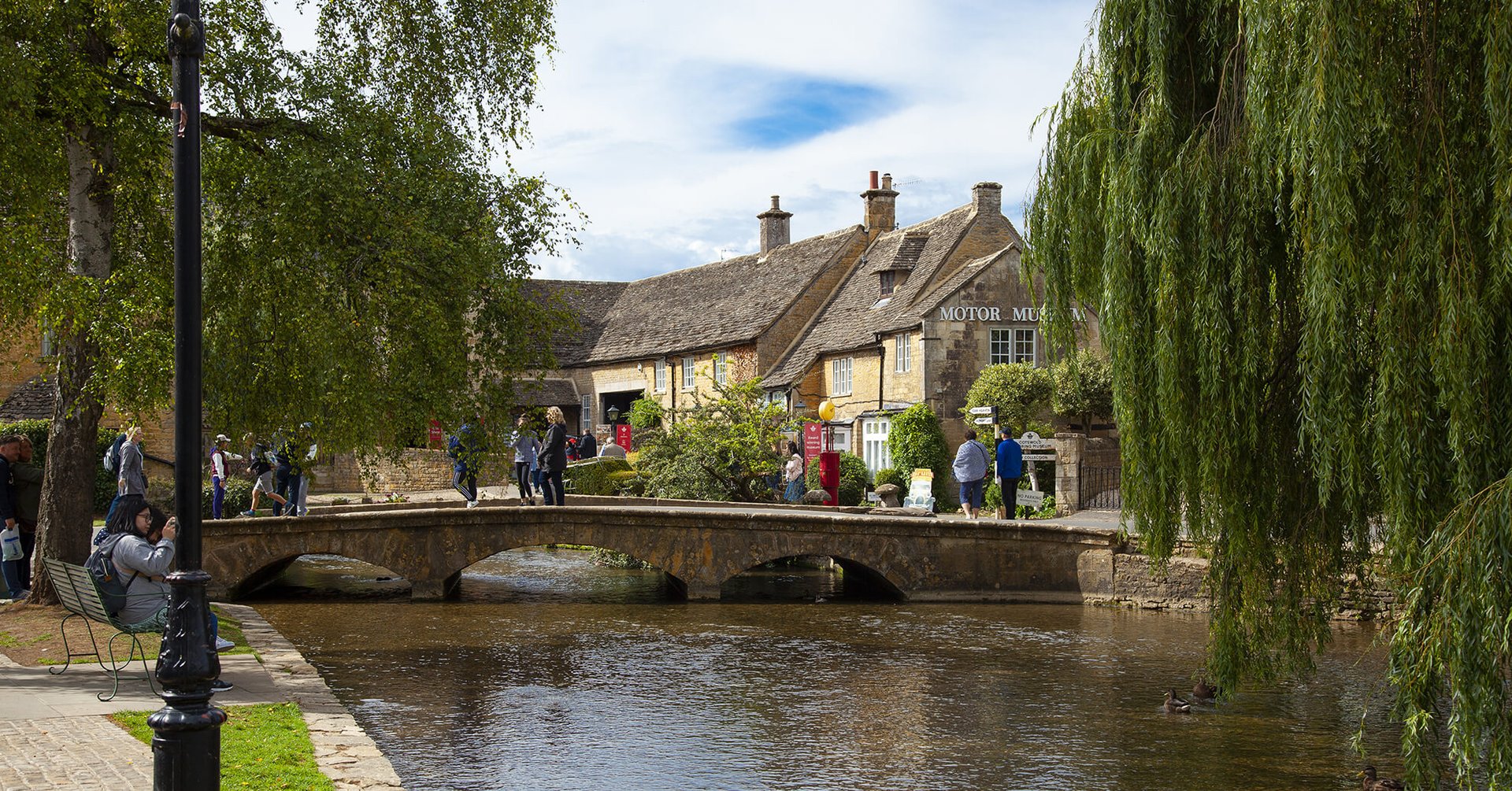 Couple strolling hand-in-hand along the River Windrush in Bourton-on-the-Water.