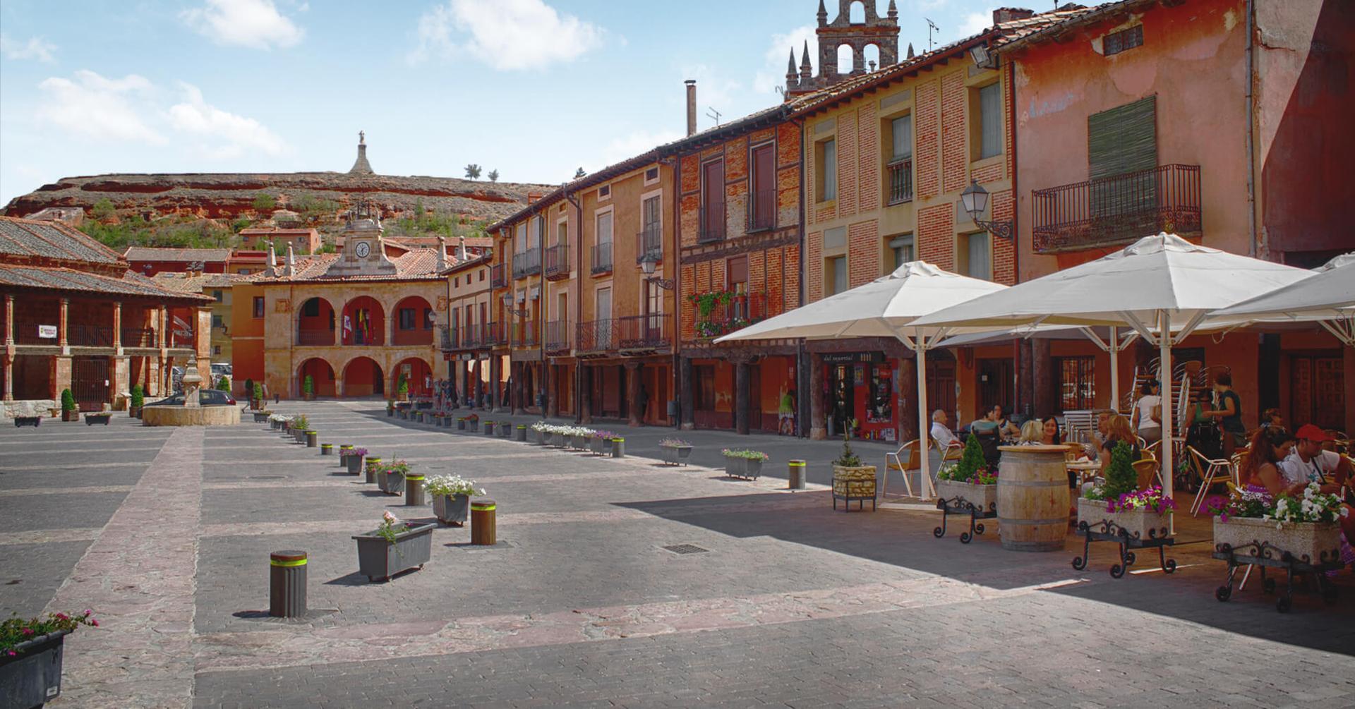 Ayllón, Segovia: Vista panorámica del pueblo medieval con murallas y casas de piedra bajo cielo azul.