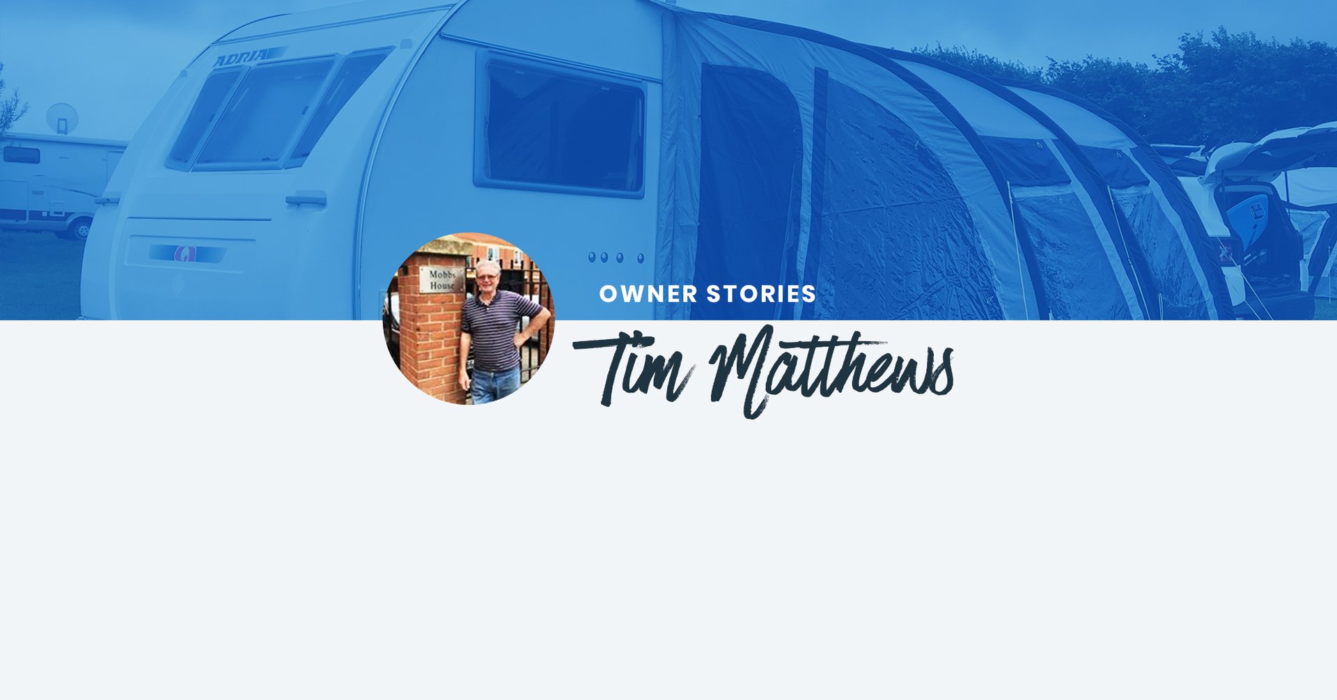 Man standing proudly next to his blue caravan on a camping adventure, with scenic backdrop.