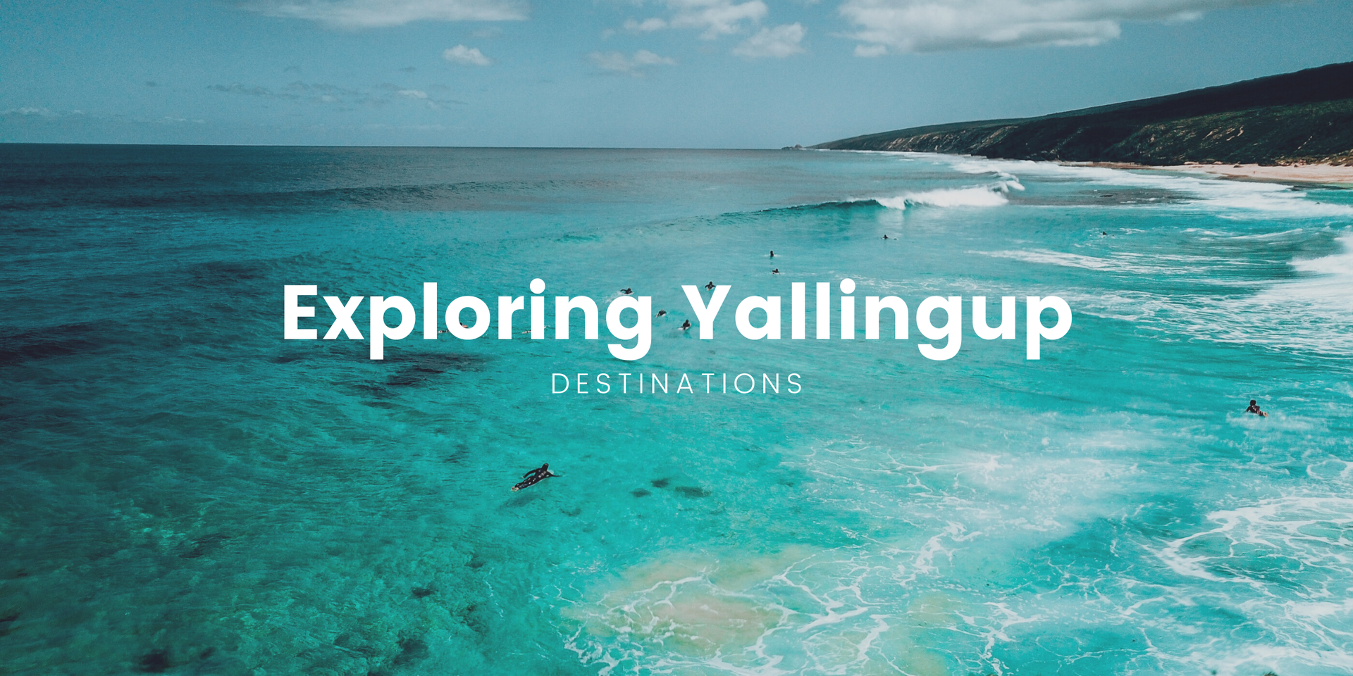 Surfer walking toward Yallingup beach with turquoise waves and rocky cliffs in the background.