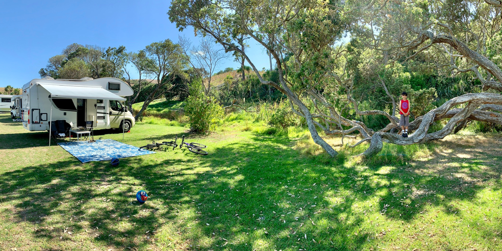 Motorhome parked up by a stunning NZ beach, ready for some family fun.