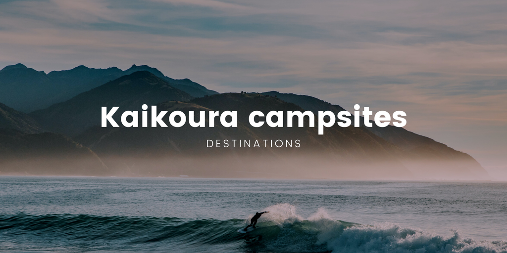 Kaikoura coastline campsite, tents pitched with campervan parked nearby, epic mountain backdrop.