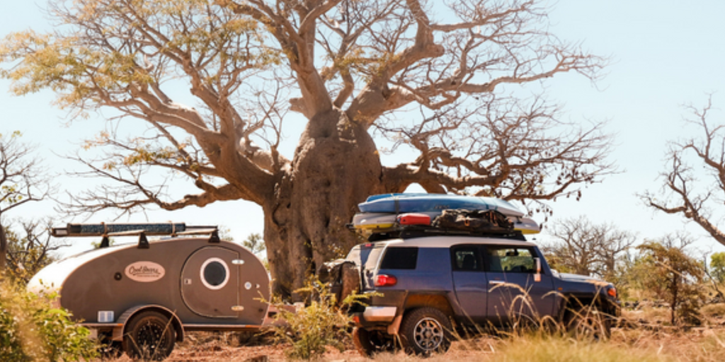 Retro caravan parked by a pristine beach, perfect for a last-minute summer getaway.