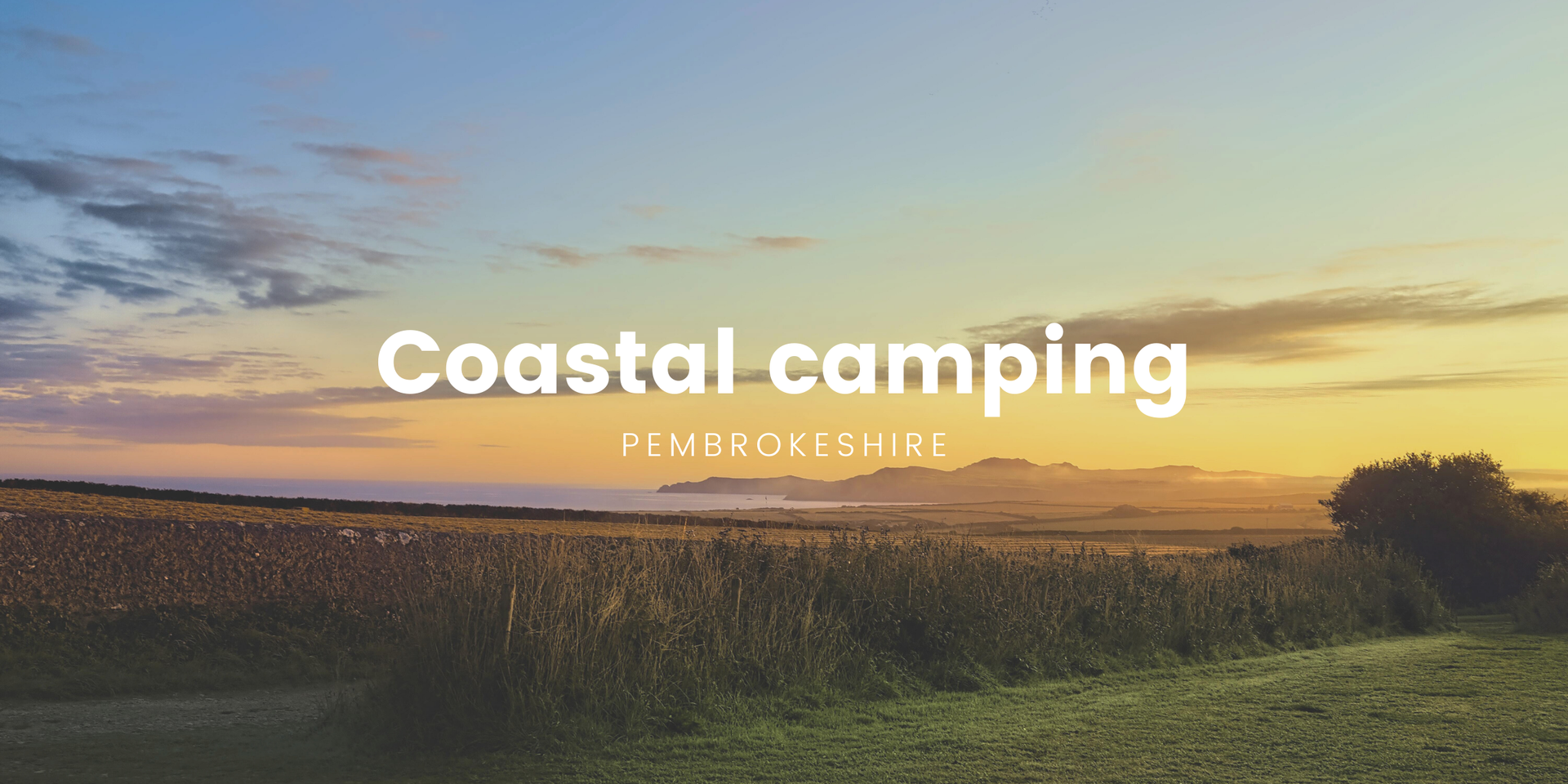 Tents pitched on Pembrokeshire coast campsite overlooking the sea, for a Welsh camping holiday.