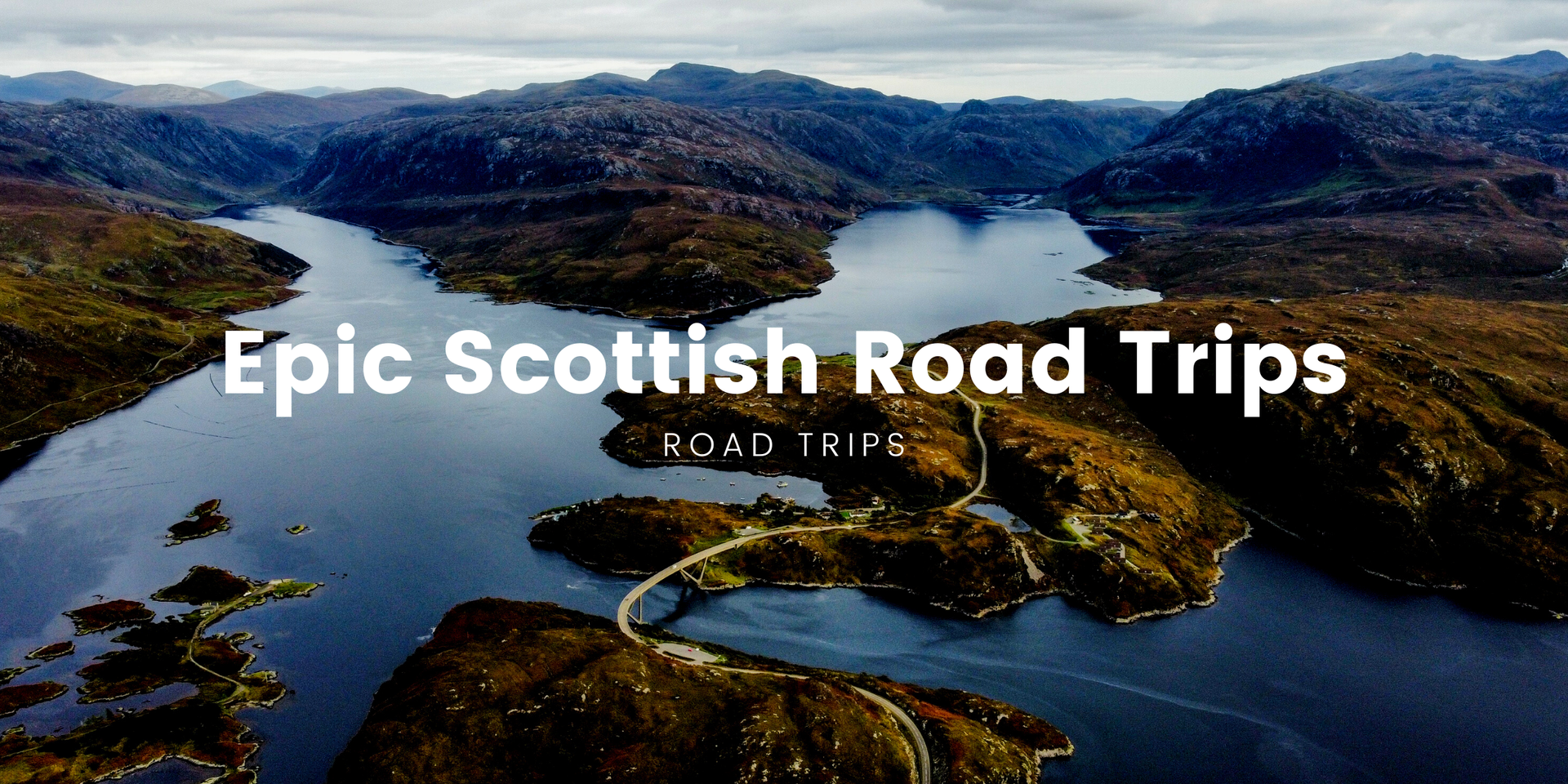 Campervan on scenic Scottish road trip, surrounded by mountains and lochs under a cloudy sky.