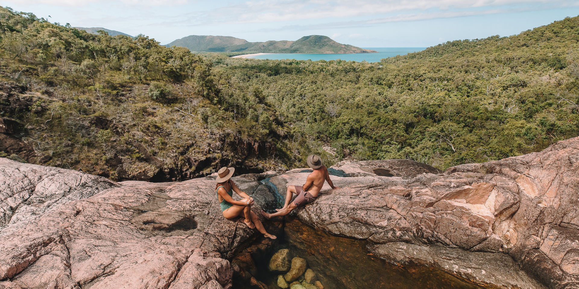 Turquoise swimming hole surrounded by lush rainforest, perfect for a Queensland summer dip.