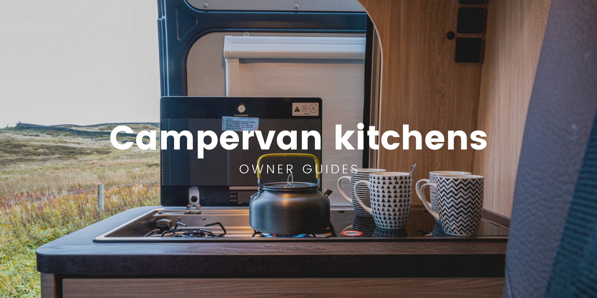 Campervan kitchen interior with view of scenic countryside through open back doors.