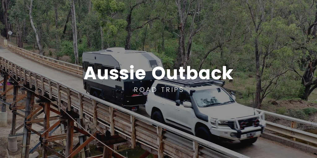 A 4WD loaded for camping cruises along a red dirt track in the Aussie outback.