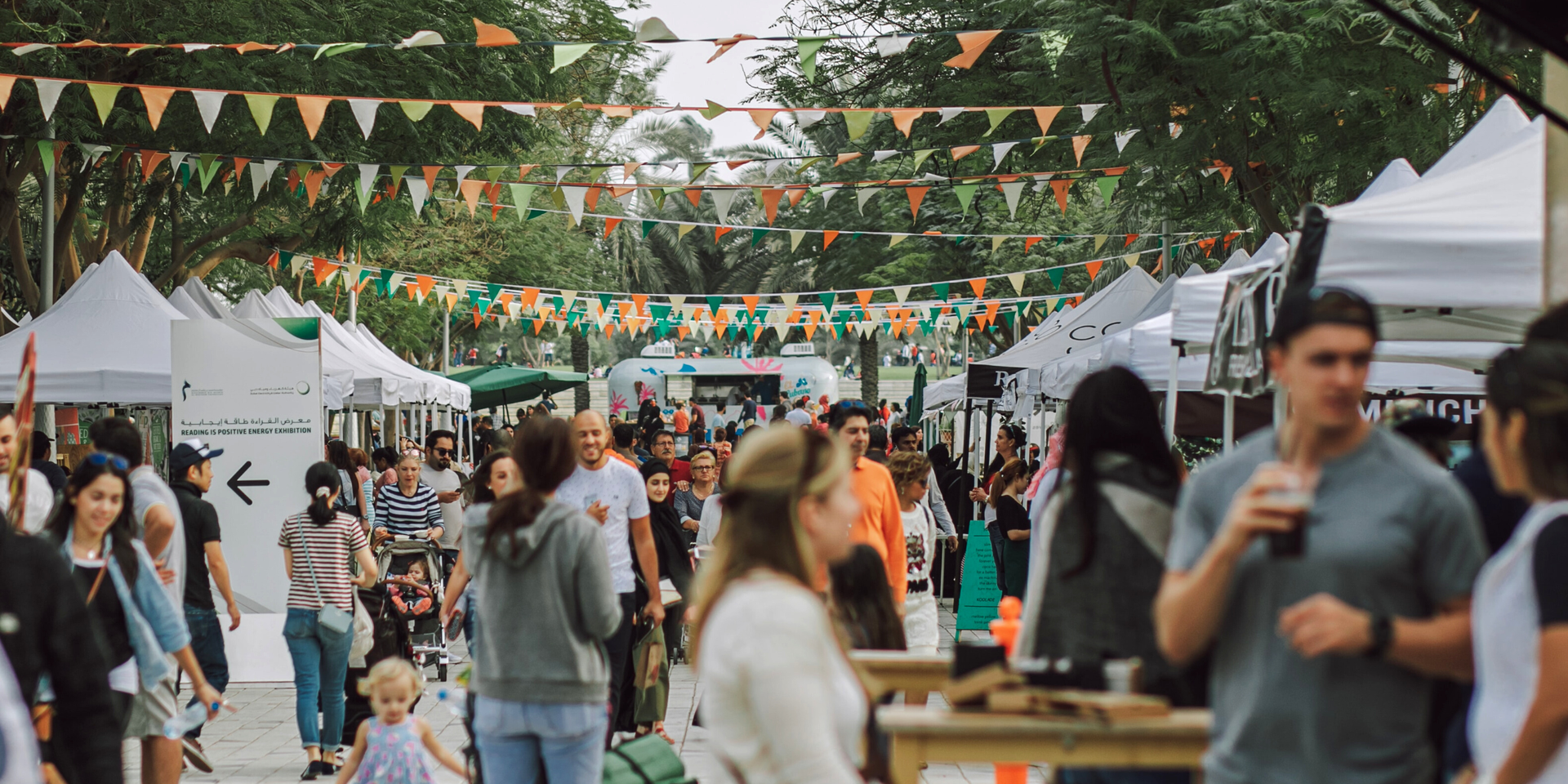 Campervan parked at a vibrant UK music festival, tents and fairy lights in the background.