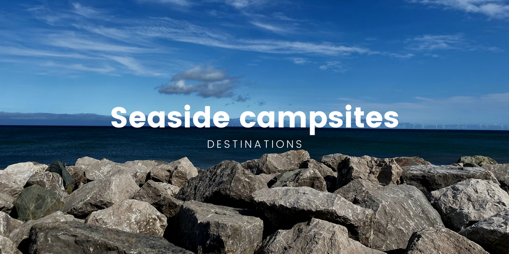 Tents pitched on a Welsh campsite overlooking a sandy beach and the sea.