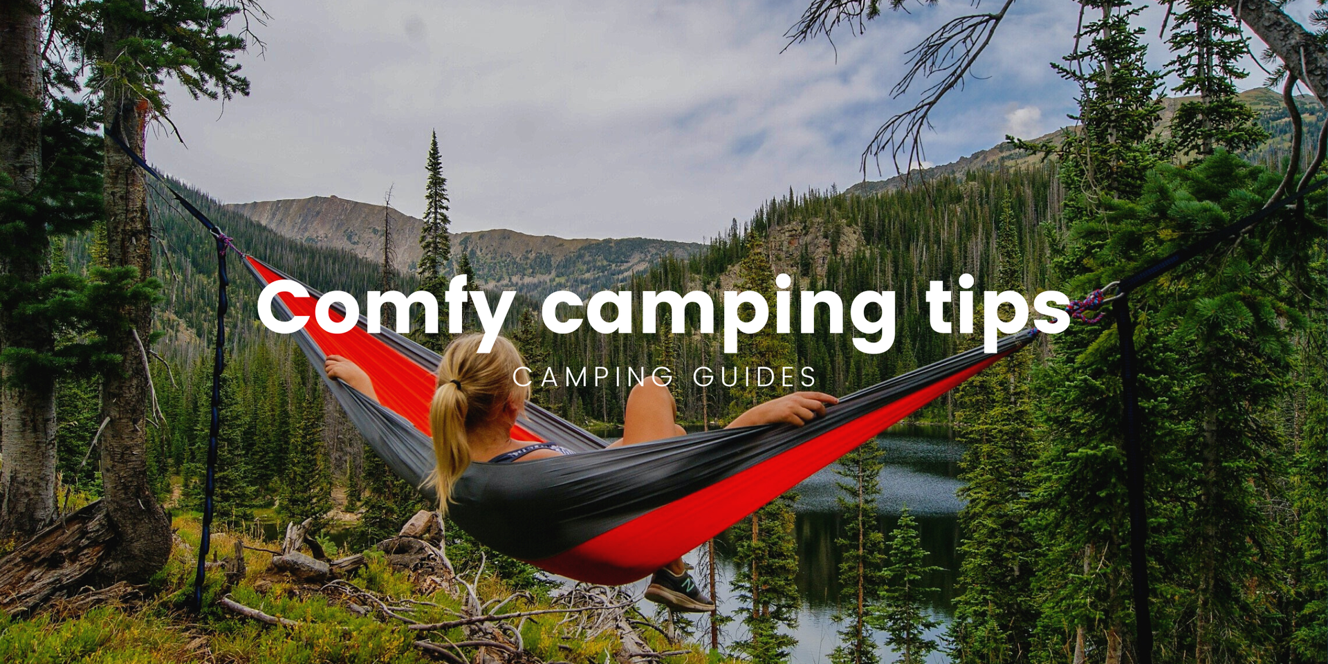 Campervan parked up in scenic campsite with rolling hills in the background, under a bright blue sky.
