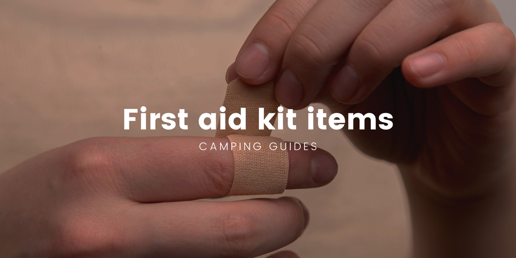 First aid kit beside a tent, with hiking boots and a water bottle. Camping in the bush.