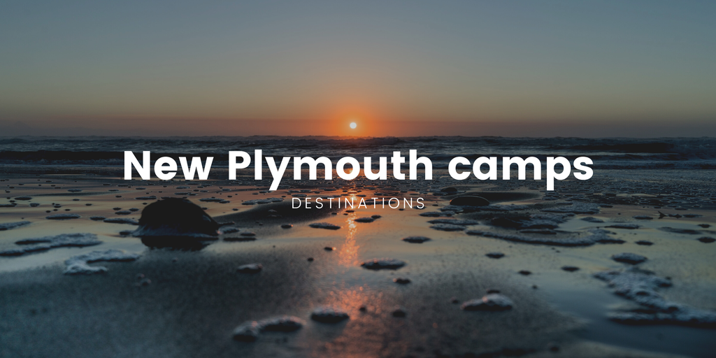 Tents pitched at a lush, green campground in Taranaki, with Mount Taranaki in the background.