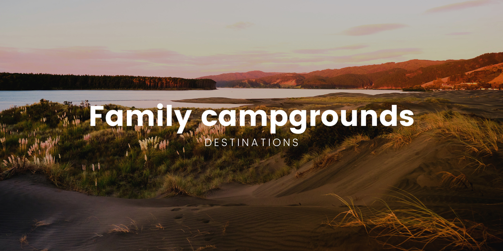 Family tent pitched at a Kiwi campground, surrounded by lush native bush.