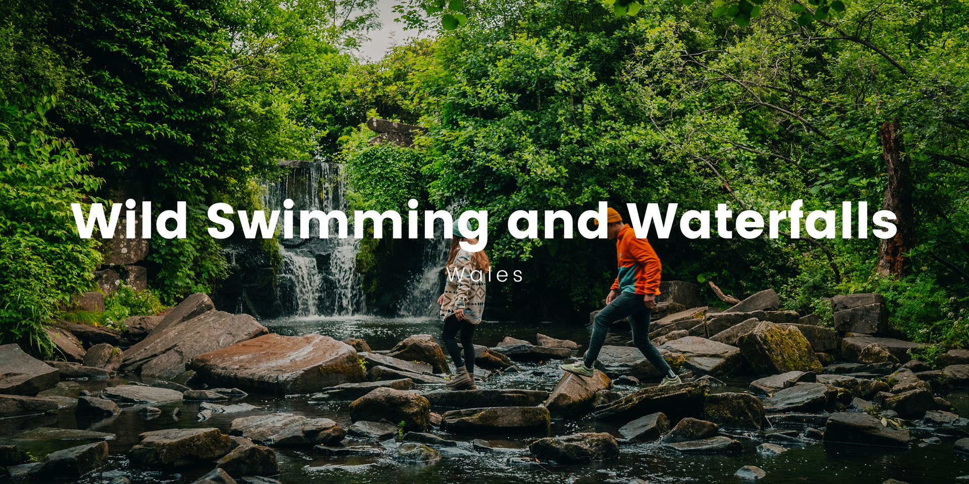 Couple wild swimming in Welsh waterfall pool on Camplify adventure; scenic countryside.