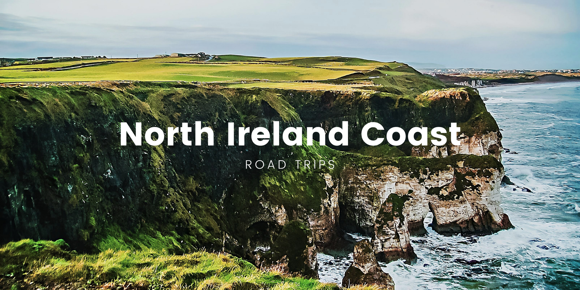 Scenic Northern Ireland coastline drive; campervan parked overlooking rugged cliffs on a sunny day.