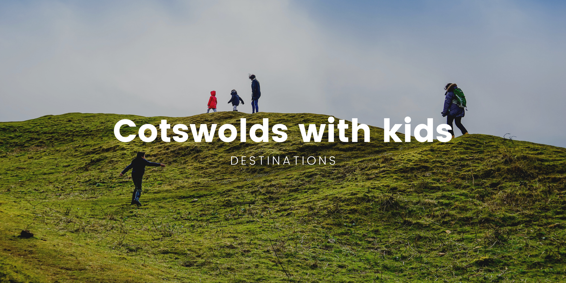 Family pitching tent at Cotswolds campsite. Rolling hills and blue skies create an idyllic camping scene.