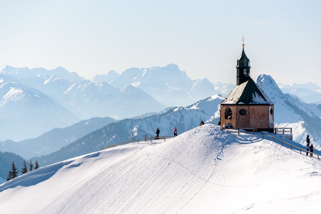 Winterlicher Campingplatz im Allgäu: Dein Wohnwagen vor verschneiter Bergkulisse lädt zur Wintercamping-Erholung ein.