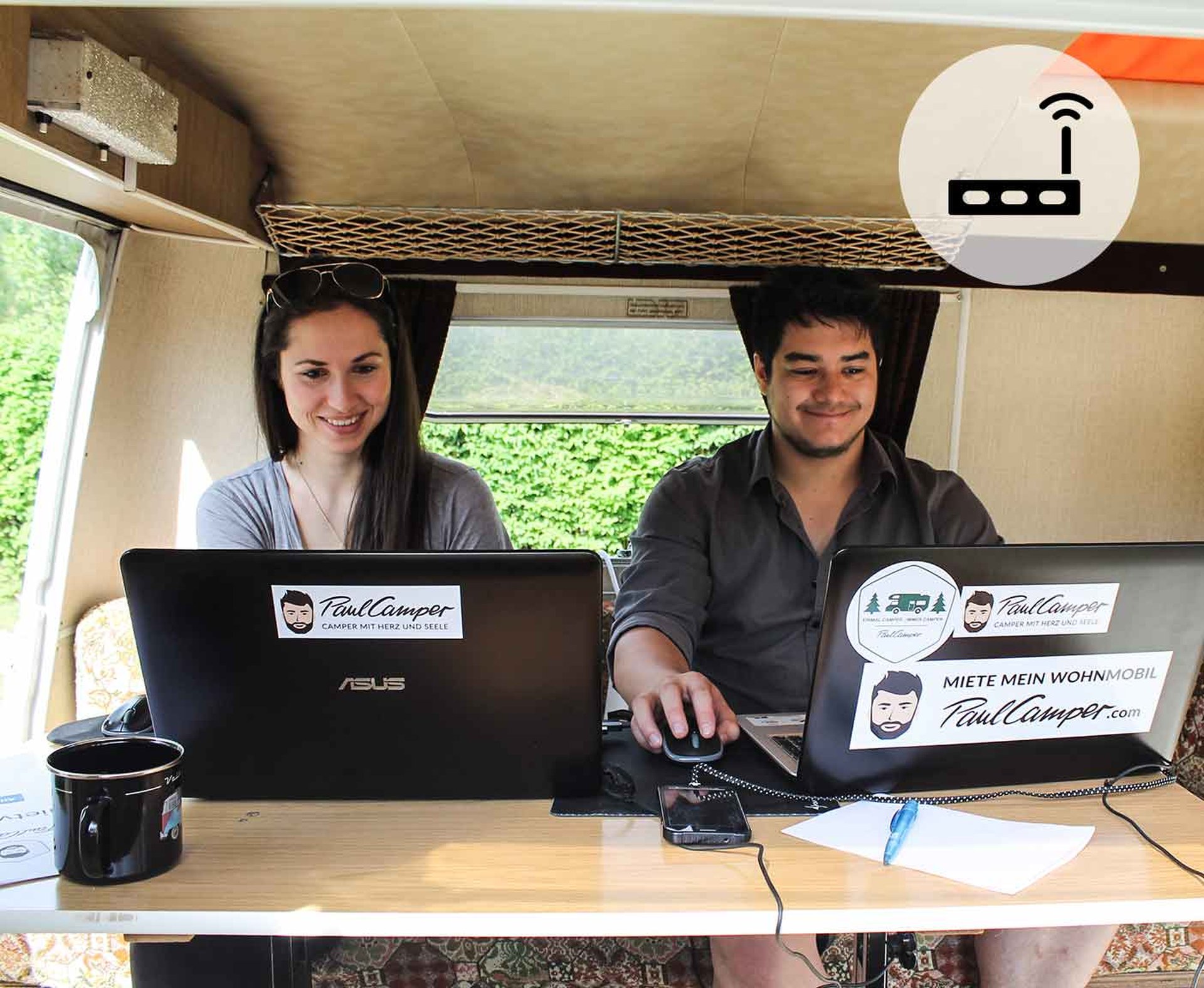 Internet im Wohnmobil, Frau und Mann arbeiten an ihren Laptops im Wohnwagen, PaulCamper, Router