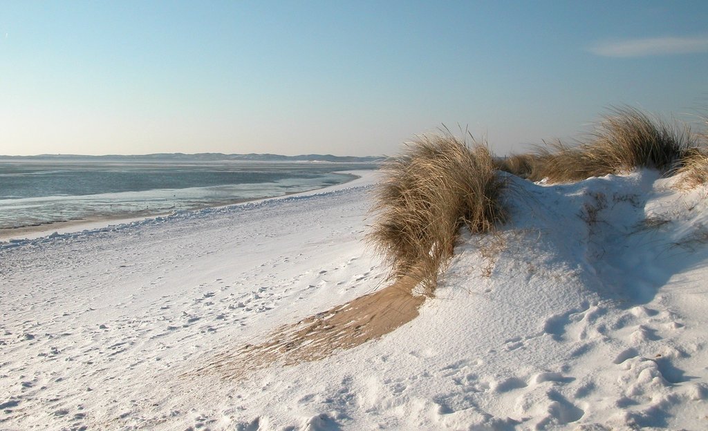 Wintercamping in Schleswig-Holstein: Dein Wohnwagen auf dem verschneiten Stellplatz am Meer für winterliche Erholung.