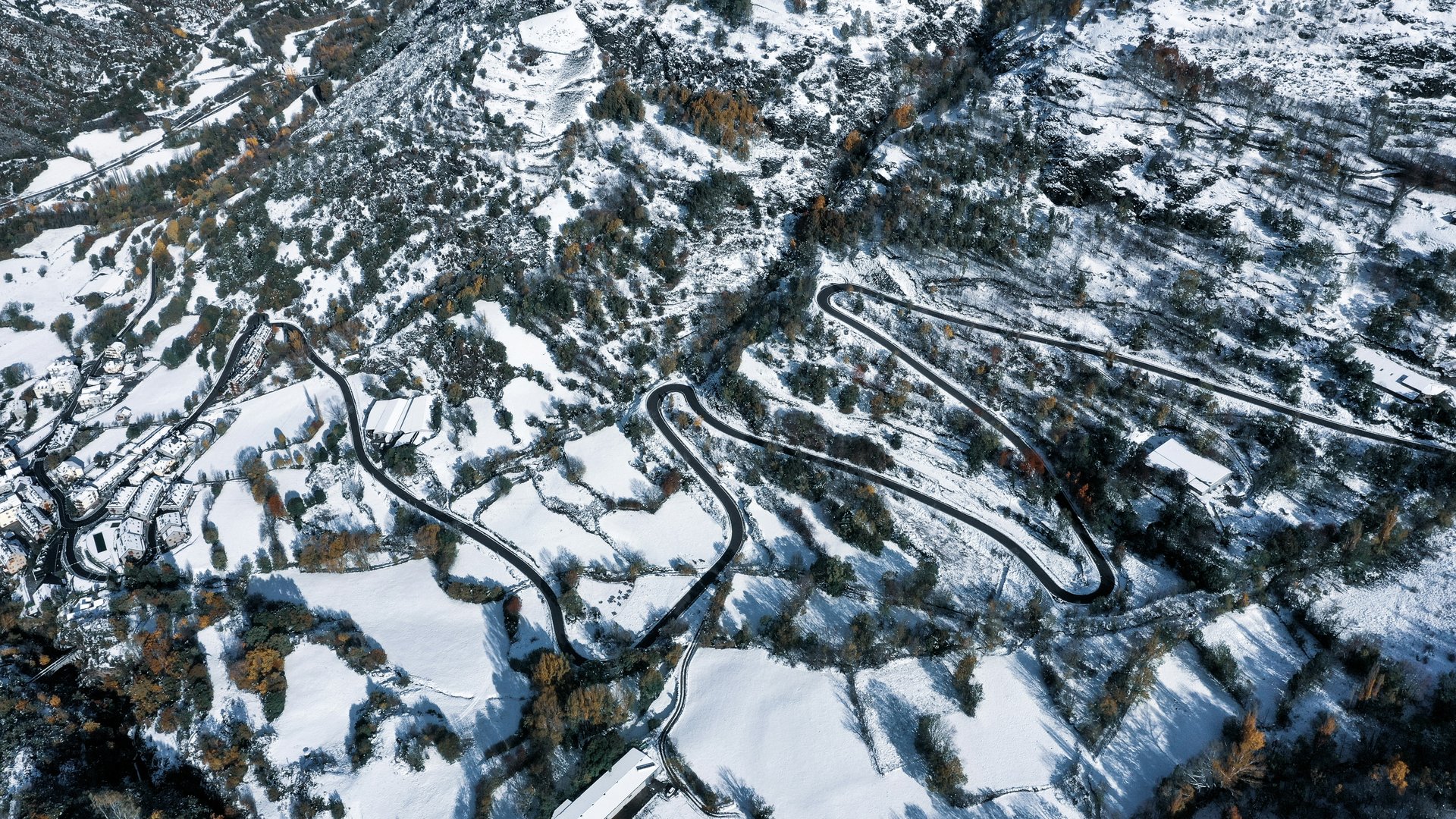Autocaravana en ruta invernal por España; montañas nevadas y cielo azul.