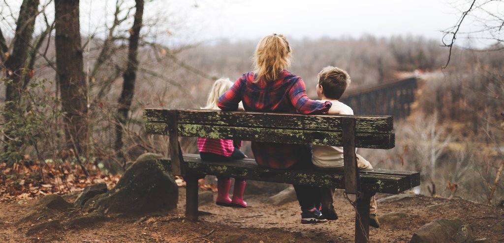 Family camping: kids playing near camper trailer in Aussie bushland setting.