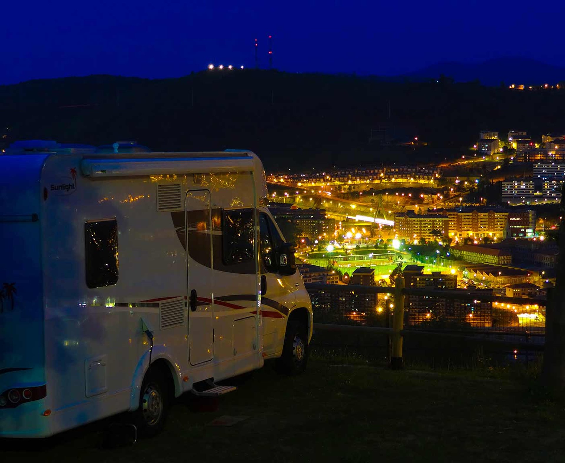 Wohnmobil in der Nacht, Lichter einer Stadt, Wohnmobil vermieten bei PaulCamper