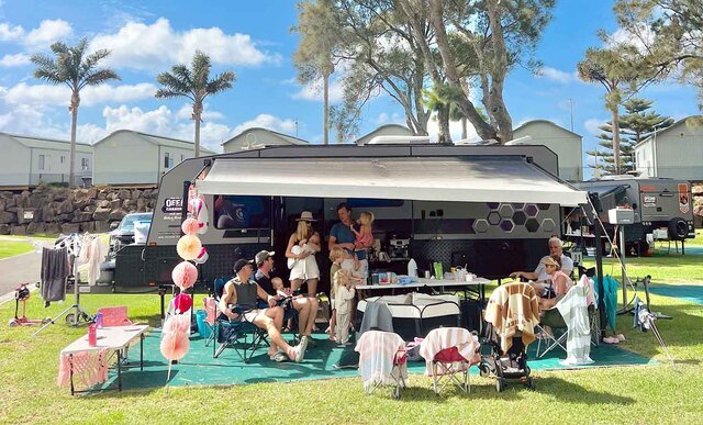 A family sitting outside a caravan having a party