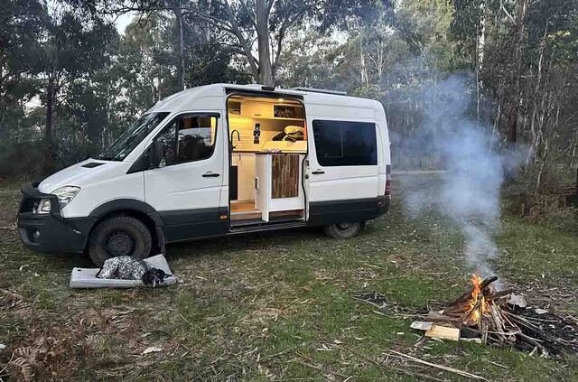 A campervan parked next to a campfire