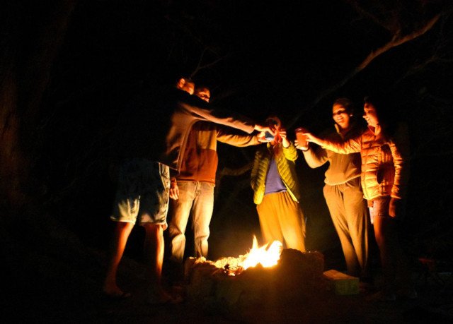 People drinking around a campfire