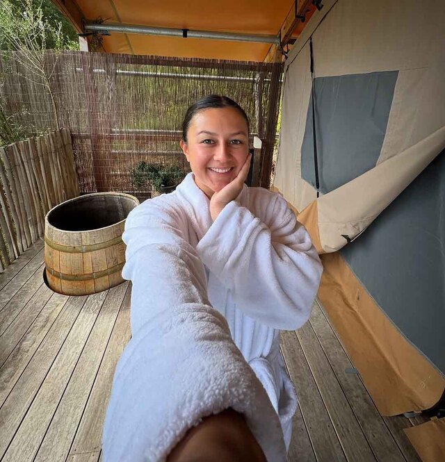 A woman in a robe standing outside of a tent