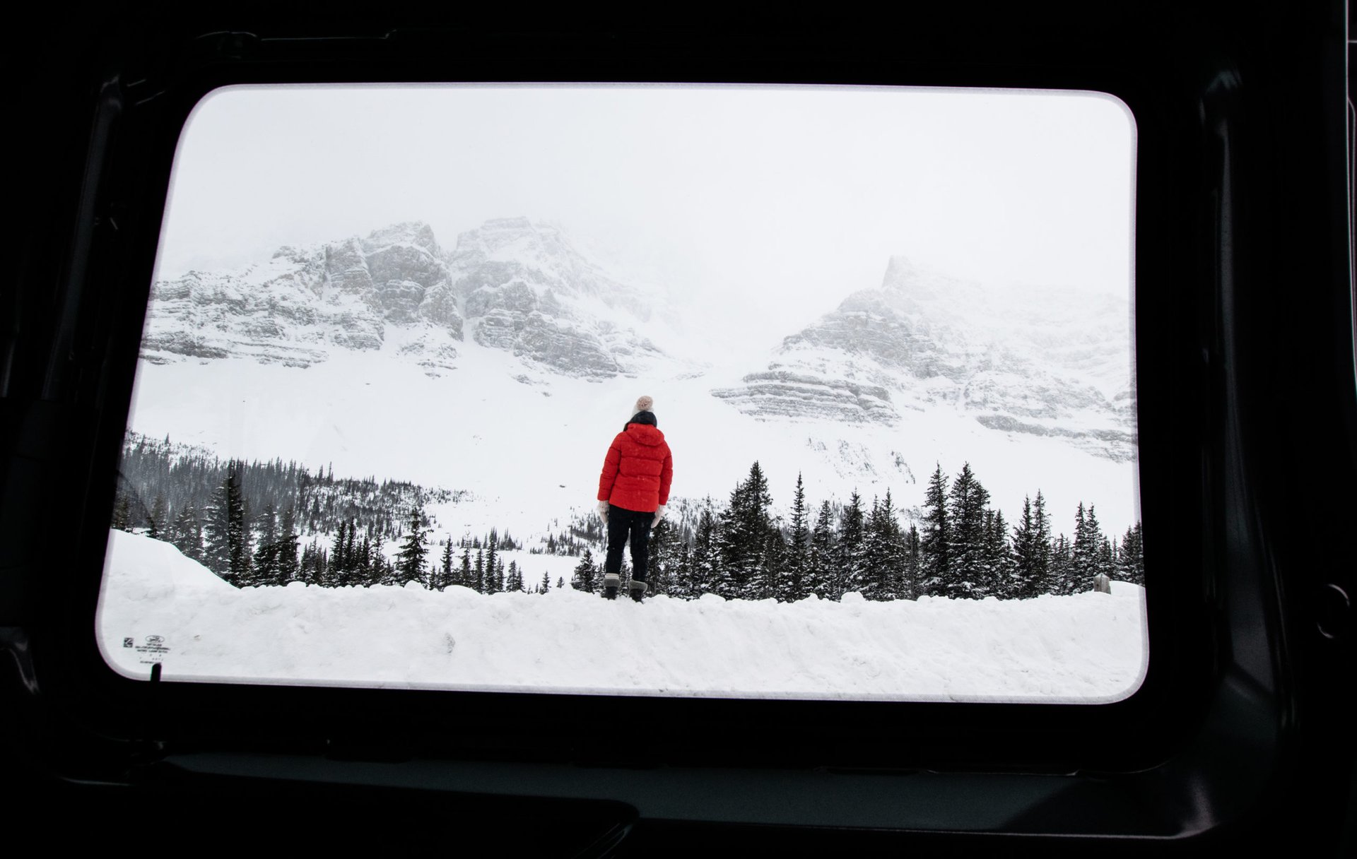 Frau in einer verschneiten Landschaft fotografiert aus dem Camper
