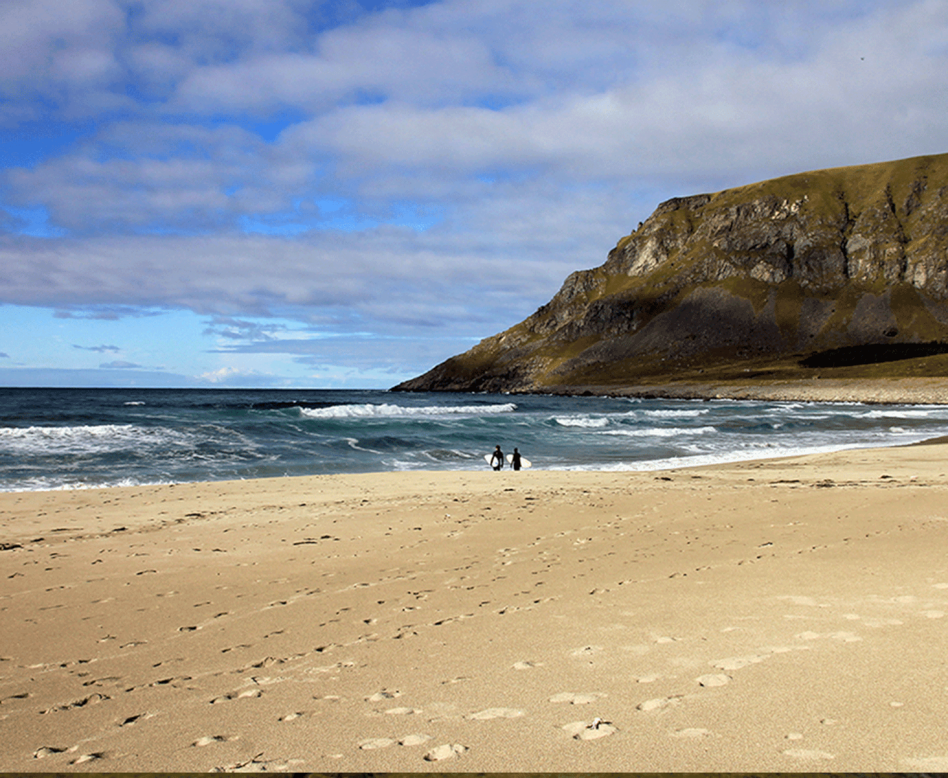 Zwei Surfer am Strand, Wellen im Meer, ein Felsen