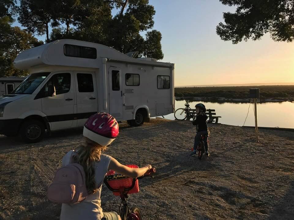 Motorhome parked at a sunny beach, Aussie flag waving. Family adventure!