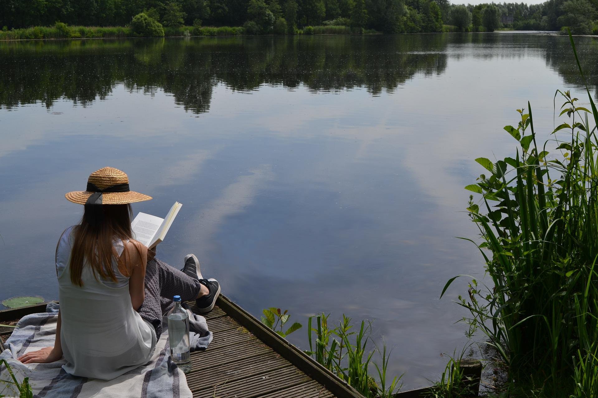 Frau am Schaalsee in Hamburg, die entspannt ein Buch liest