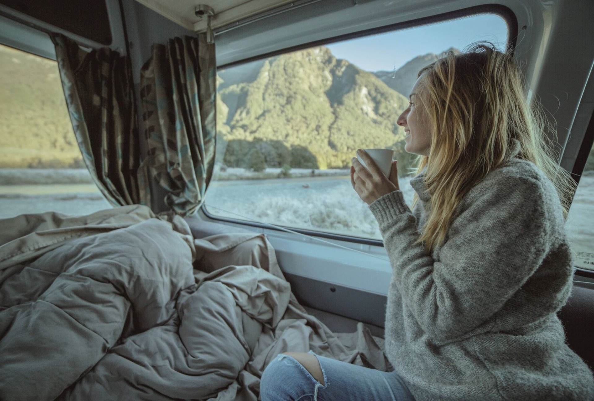 Theedrinkende vrouw kijkt uit haar caravan