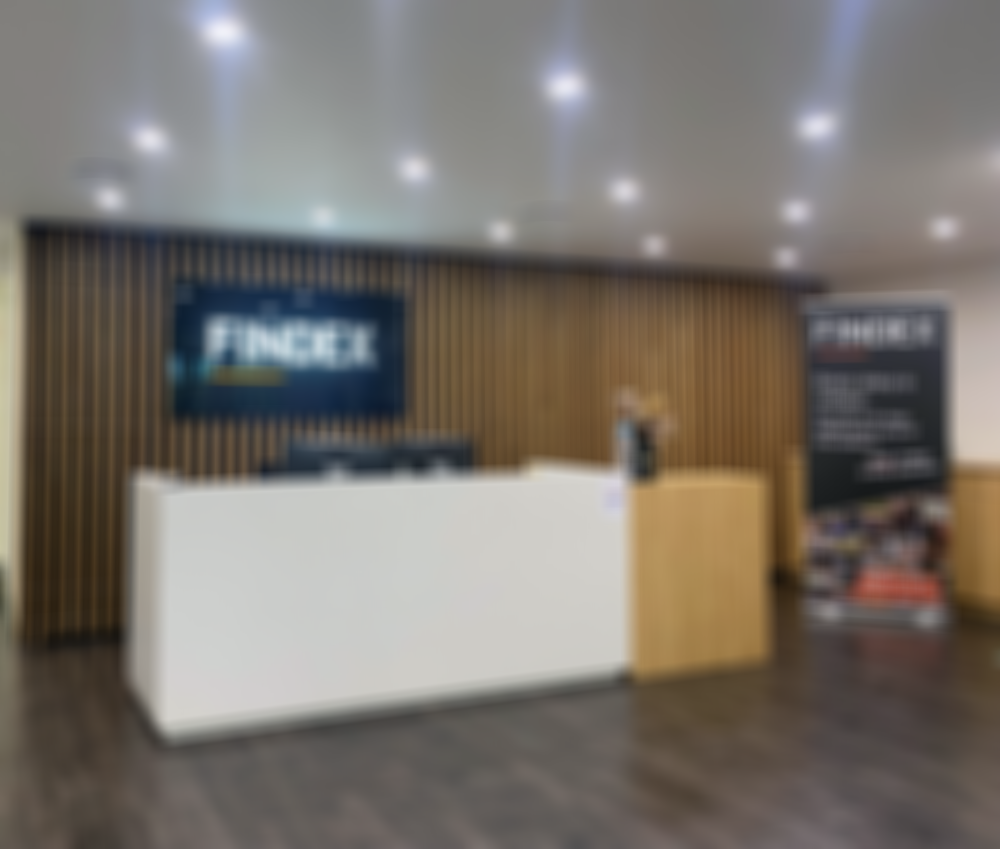 Modern office reception area with a white desk, Findex logo on the wall, and a promotional banner. Wood paneling and dark flooring enhance the decor.