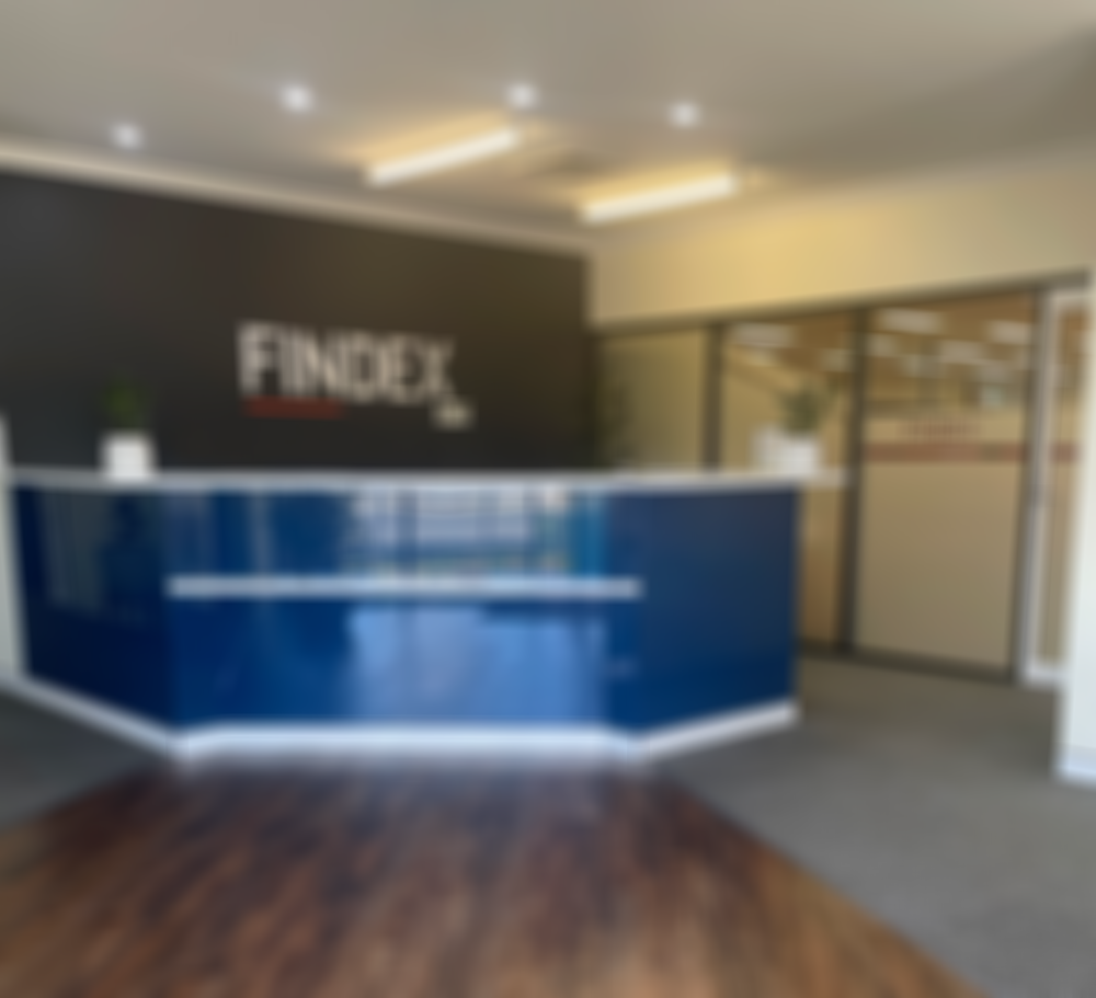 Modern office reception area with a dark blue and white desk, "FINDEX" logo on the wall, potted plants, and glass doors.