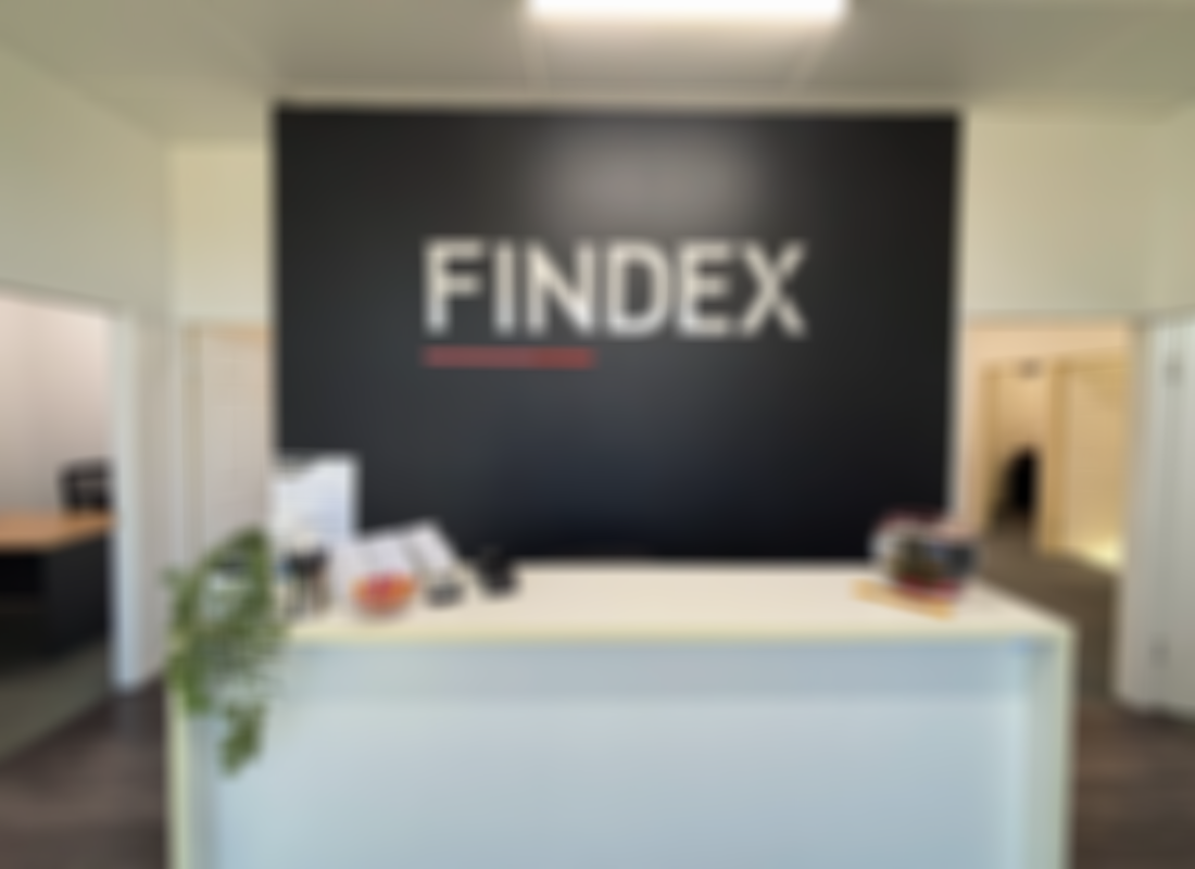 Findex Burdekin office reception desk. White desk with plant and business cards on top, Findex logo on dark background behind desk.
