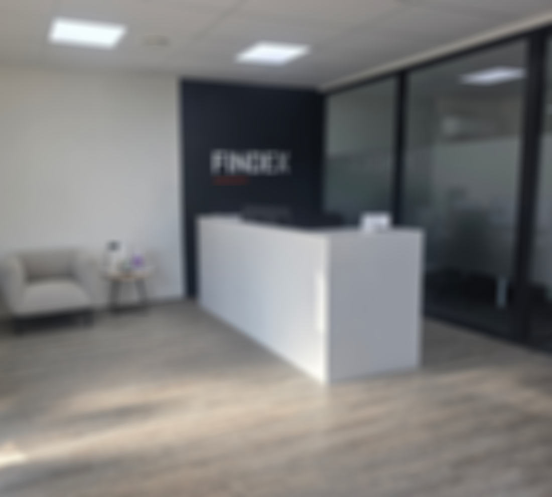 Findex Te Awamutu office reception area with a white desk, a grey cushioned chair, and a small table with magazines. The wall displays the "FINDEX" logo.