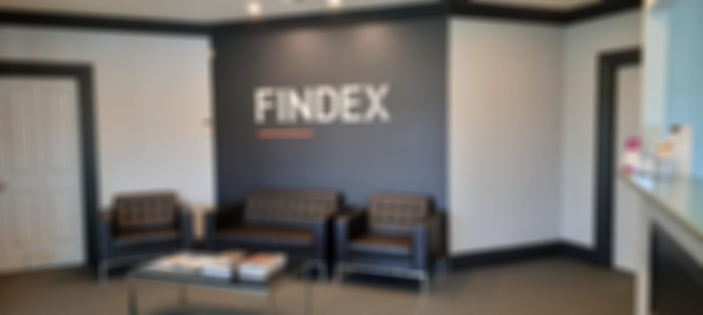 Findex Stawell office waiting area, with "FINDEX" logo on a dark accent wall, three black tufted leather seats and a magazine-covered glass coffee table.