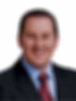 Jon Witheford smiling in a suit with a red tie and blue shirt, against a white background.