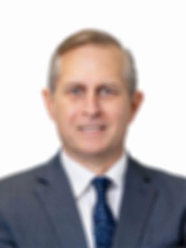 Michael Pagel in a suit and tie smiles slightly against a plain white background.