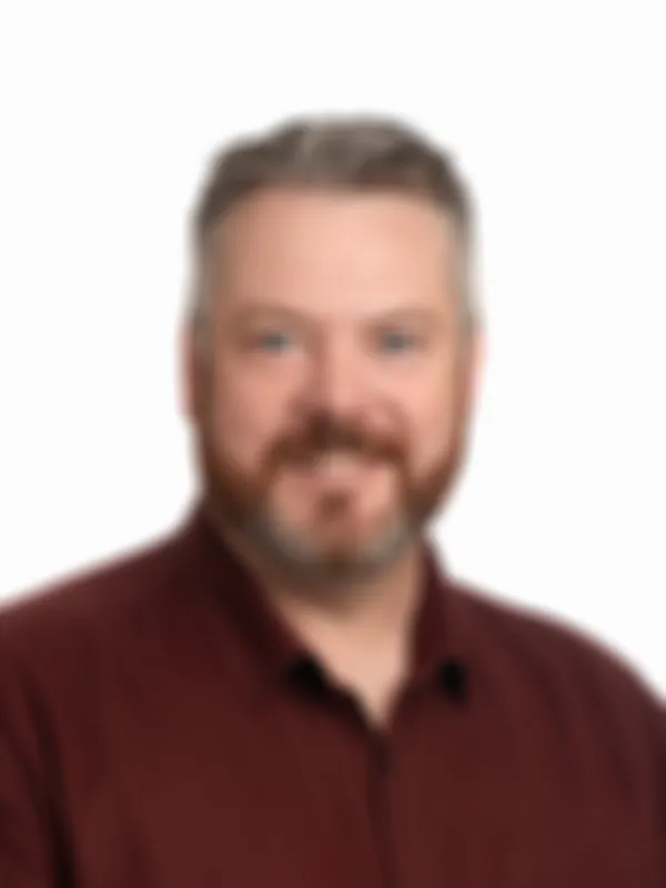 Chris Parkinson smiling, wearing a maroon shirt against a plain white background.