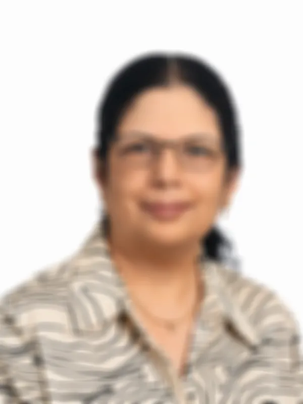 Aruna Baskaran in a patterned shirt smiles slightly against a plain white background.