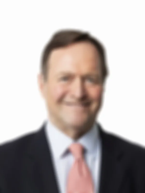 Smiling man in a suit with a light blue shirt and pink tie, on a white background.