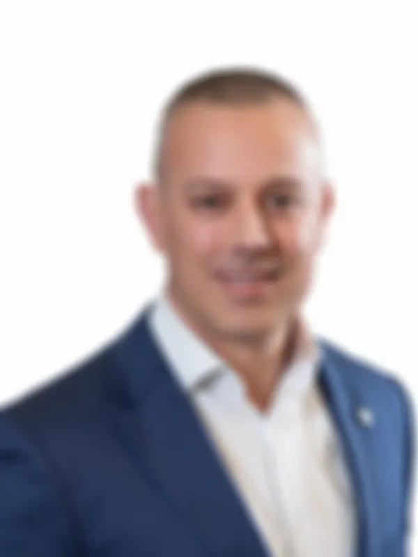 Simon Warner in a blue suit and white shirt, against a white background.